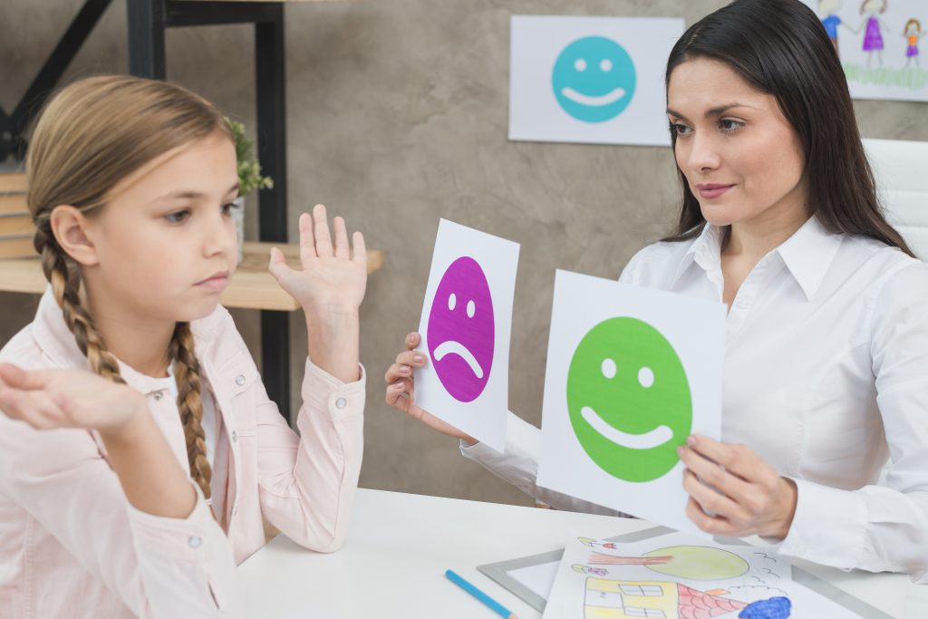 Educación emocional en los centros educativos. Psicóloga mostrando tarjetas de emociones a una niña