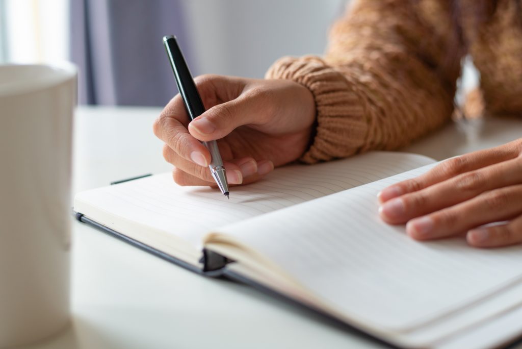 Primer plano de mujer sentada a la mesa y escribiendo