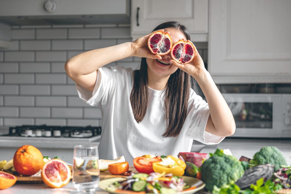 mujer joven cocinando contenta alimentos saludables