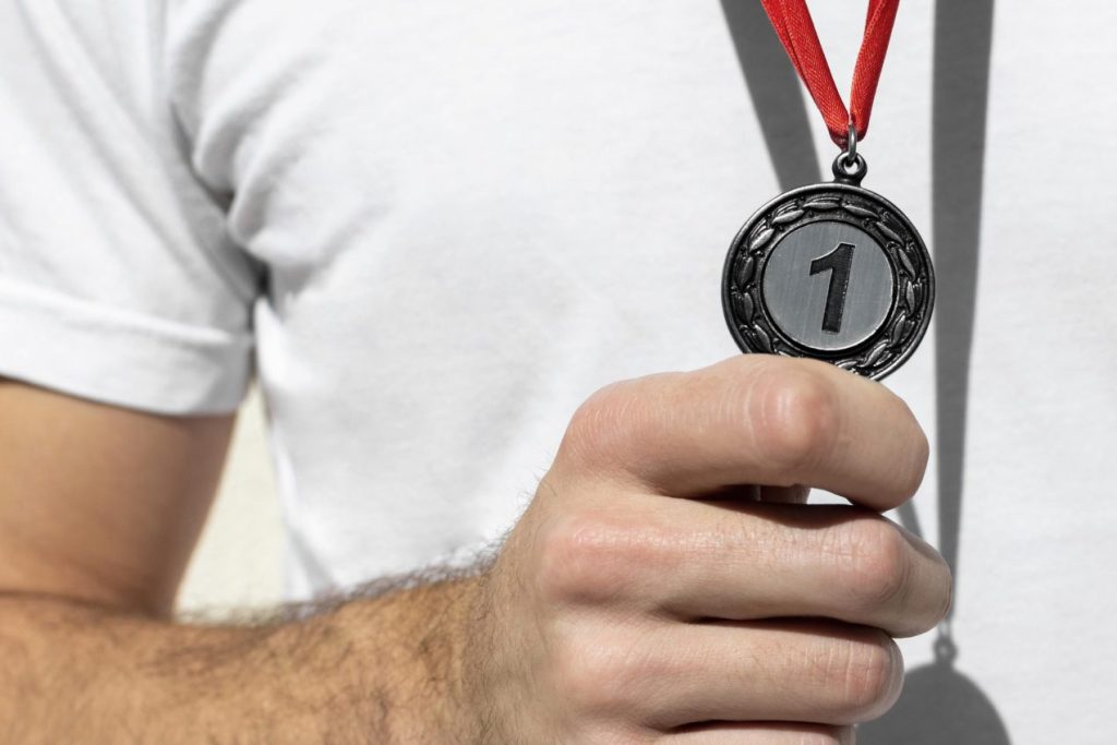 hombre sujetando medalla número uno